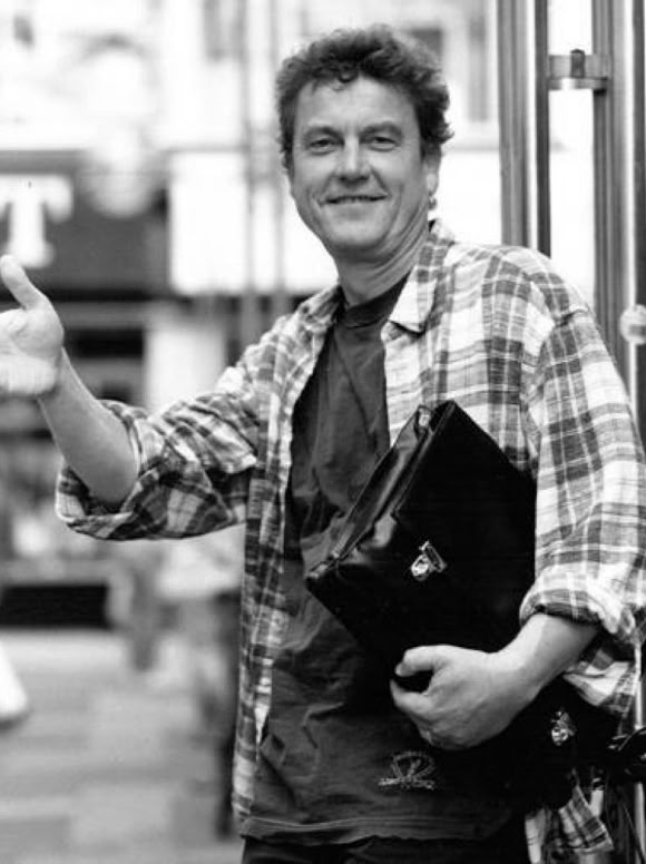 Lutz G&ouml;rner in einem karierten Hemd steht auf einer Stra&szlig;e und h&auml;lt eine schwarze Tasche, w&auml;hrend er mit der anderen Hand gestikuliert. Im Hintergrund sind unscharfe Geb&auml;ude und Menschen zu sehen.